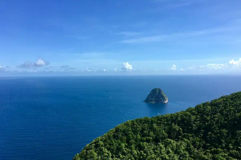 Le rocher du Diamant, îlot escarpé au large de la côte sud de la Martinique, sous un ciel bleu.